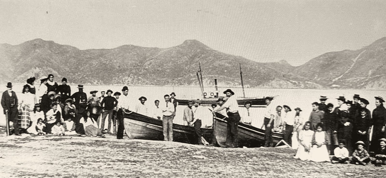 Whalers and their families on the beach at Te Awaiti, with whaleboats drawn up and a steamer behind